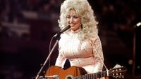American singer, songwriter and actress Dolly Parton, performs with a guitar, 1976.