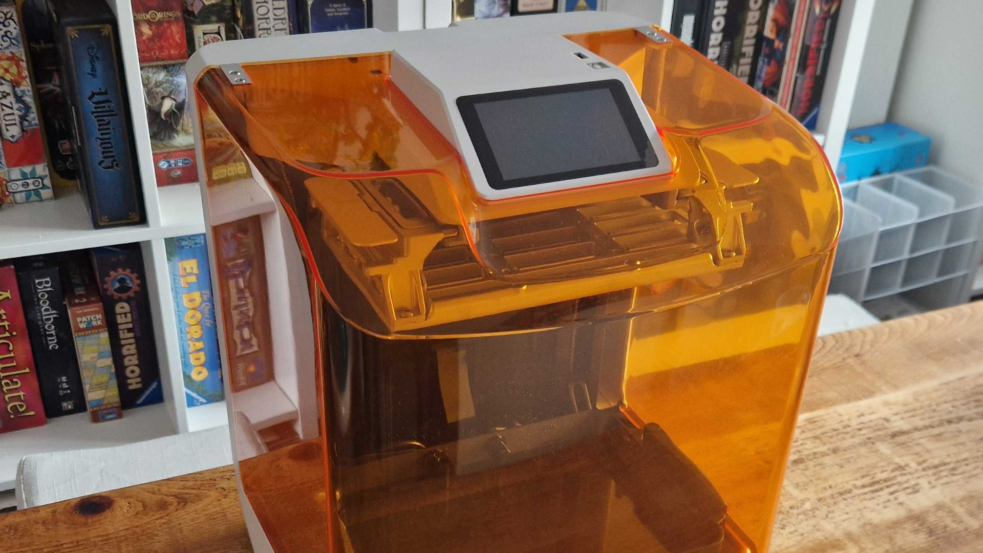 Creality Halot-X1 printer on a wooden table, with a board game shelf unit visible behind it