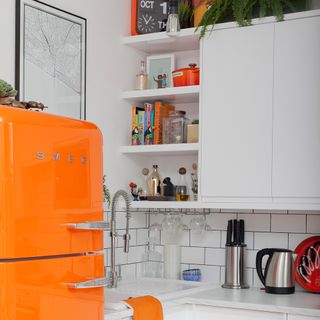 white kitchen with orange fridge and storage shelves