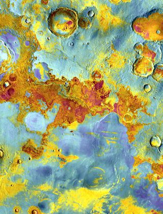 False-color view of part of Meridiani Planum, about 250 miles (400 kilometers) northeast of where Mars rover Opportunity landed. The image was taken from NASA’s Mars Odyssey orbiter using its Thermal Emission Imaging System (THEMIS) - a camera that images Mars in 5 visible and 10 infrared “colors.” The image combines daytime and nighttime infrared views. Reddish areas have more rocks and hardened sediments, while bluish areas feature more dust, sand, and fine-grain material. Image