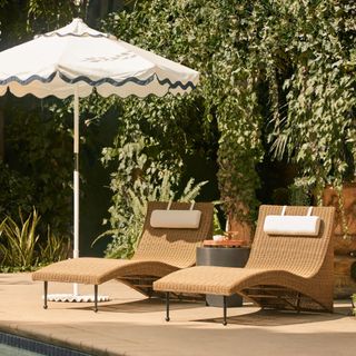 Poolside patio with rattan loungers and blue and white sun umbrella