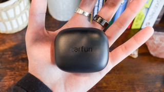 An EarFun Air Pro 3 case sitting in the palm of a hand.