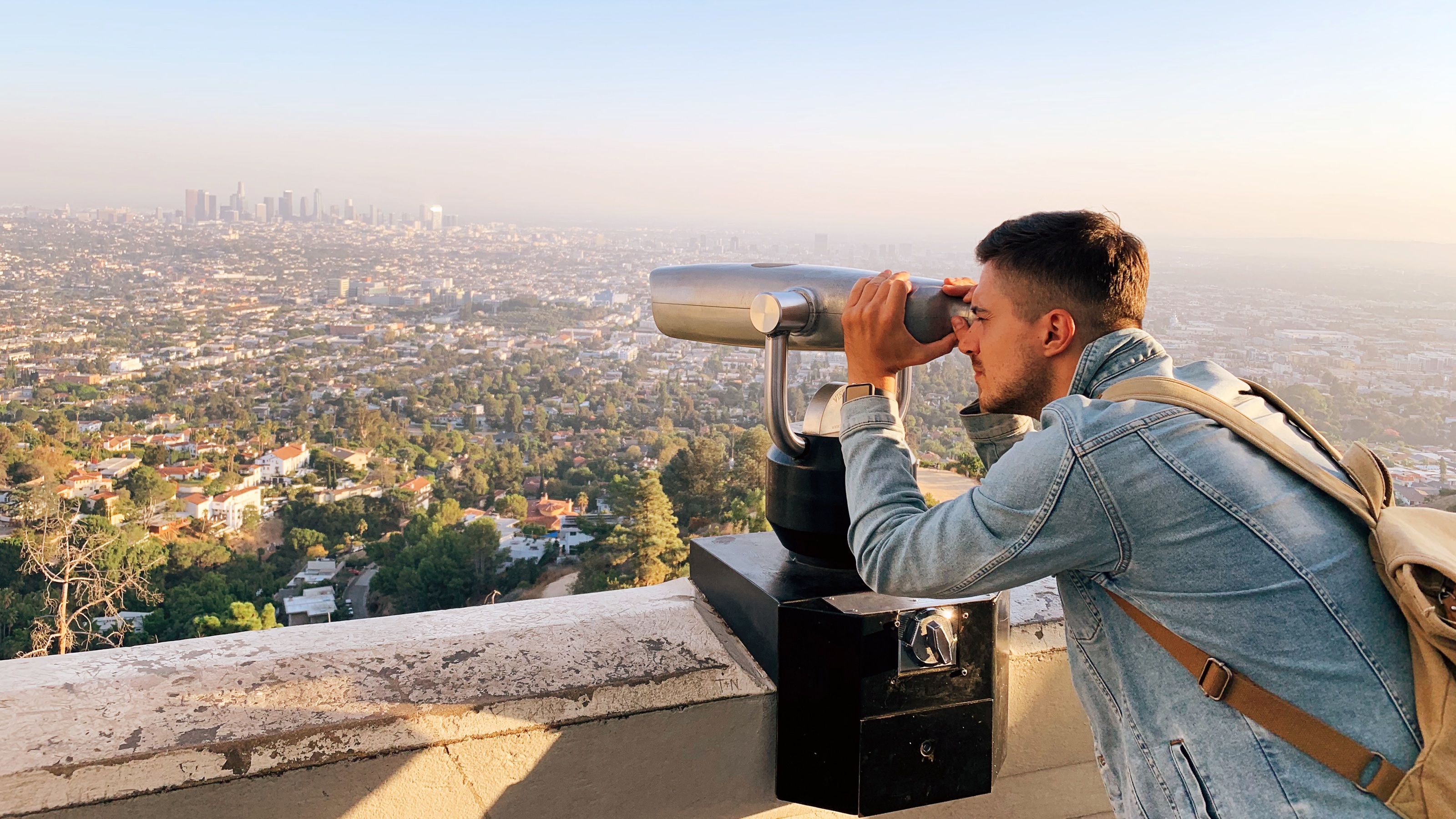 A young man looks at scenery through binoculars. 