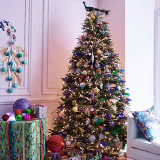 A living room with an extravagantly decorated Christmas tree finished with a peacock decoration on top