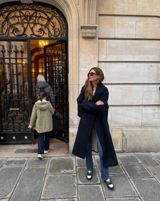 Woman wearing black coat in front of Parisian-style doorway