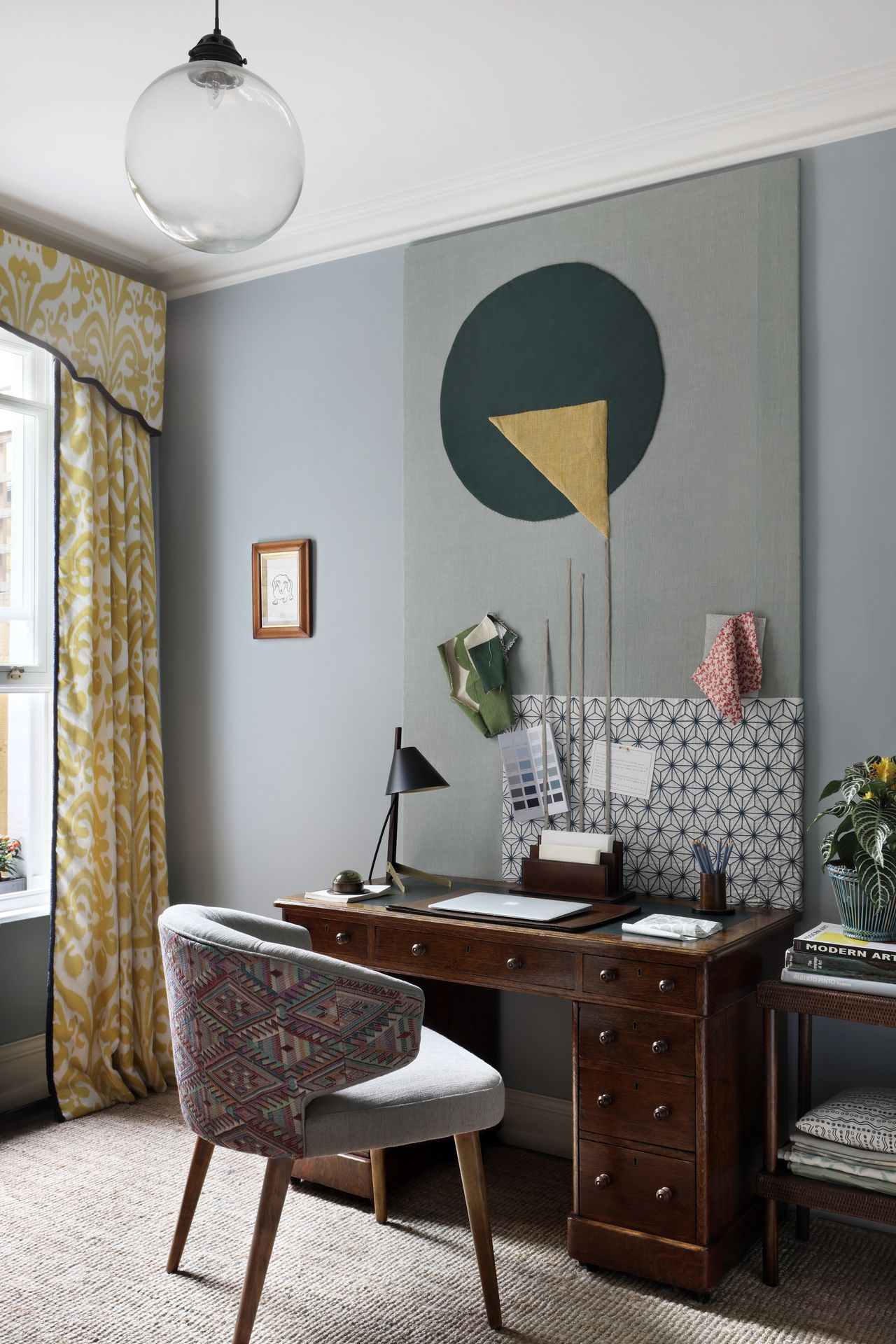 Home office with upholstered pin board and yellow curtains