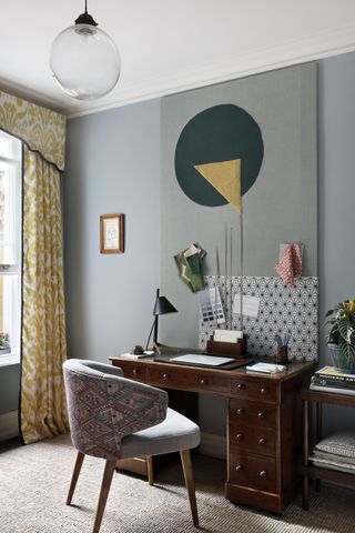 home office with upholstered pinboard and yellow curtains