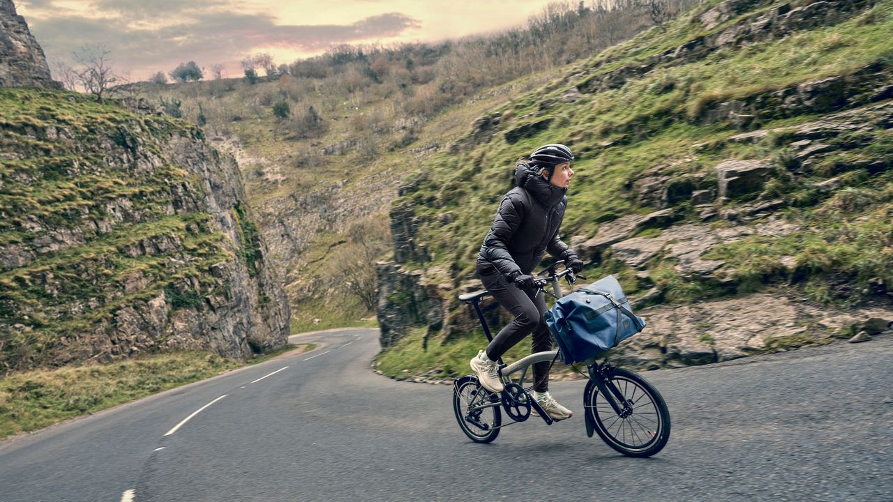 A 12-speed Brompton T-Line folding bike being ridden up a steep climb