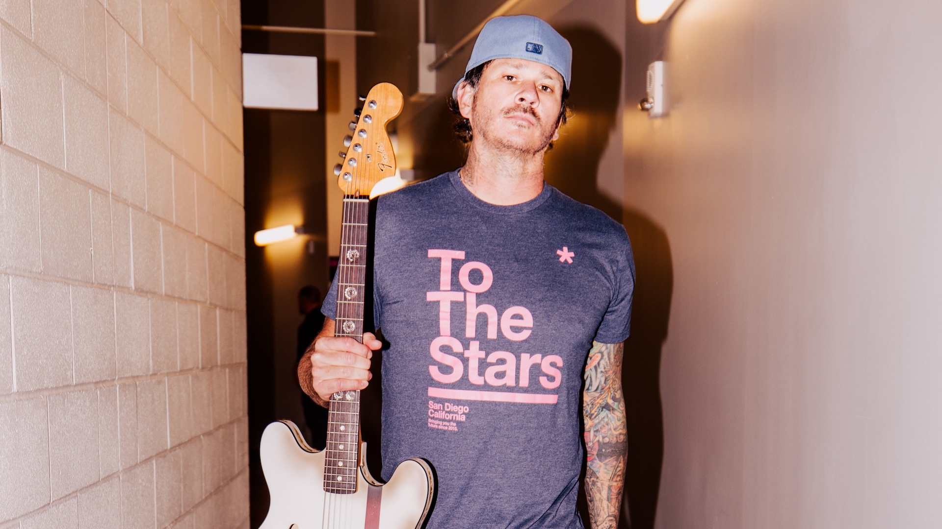 Musician Tom DeLonge holding a guitar