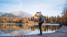 A woman hiker in autumn nature, using binoculars