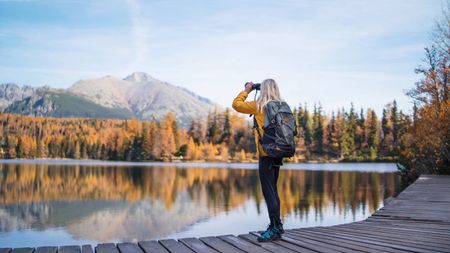 A woman hiker in autumn nature, using binoculars