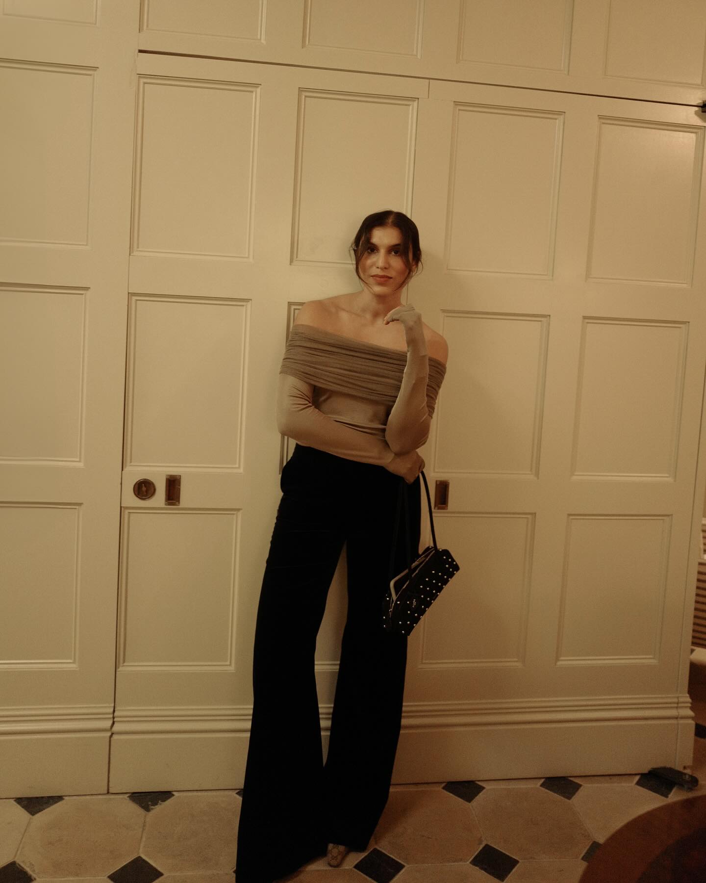 An image of @india.cardona wearing a sheer khaki top with black wide-leg trousers.