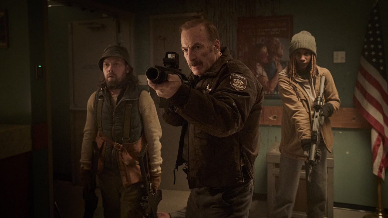 Bob Odenkirk holding a gun, standing ahead of Brendan Fletcher and Reena Jolly in Normal