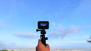 En GoPro Hero 10 Black hålls upp för att filma himlen.