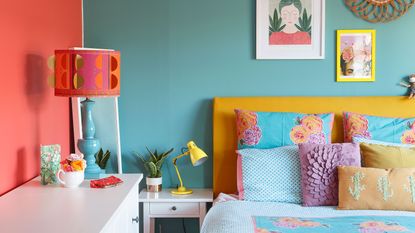 bedroom with blue and coral walls, yellow headboard and patterned cushions