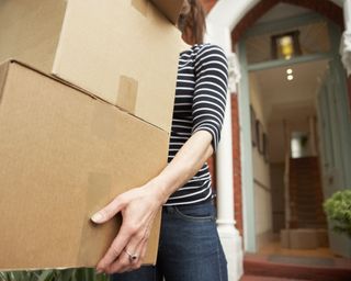 woman carrying moving boxes out of house