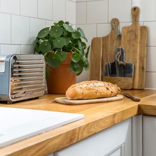 A kitchen worktop with bread on a cutting board and other cutting boards in the background