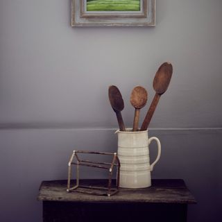 White vase filled with assortment of wooden spoons on table