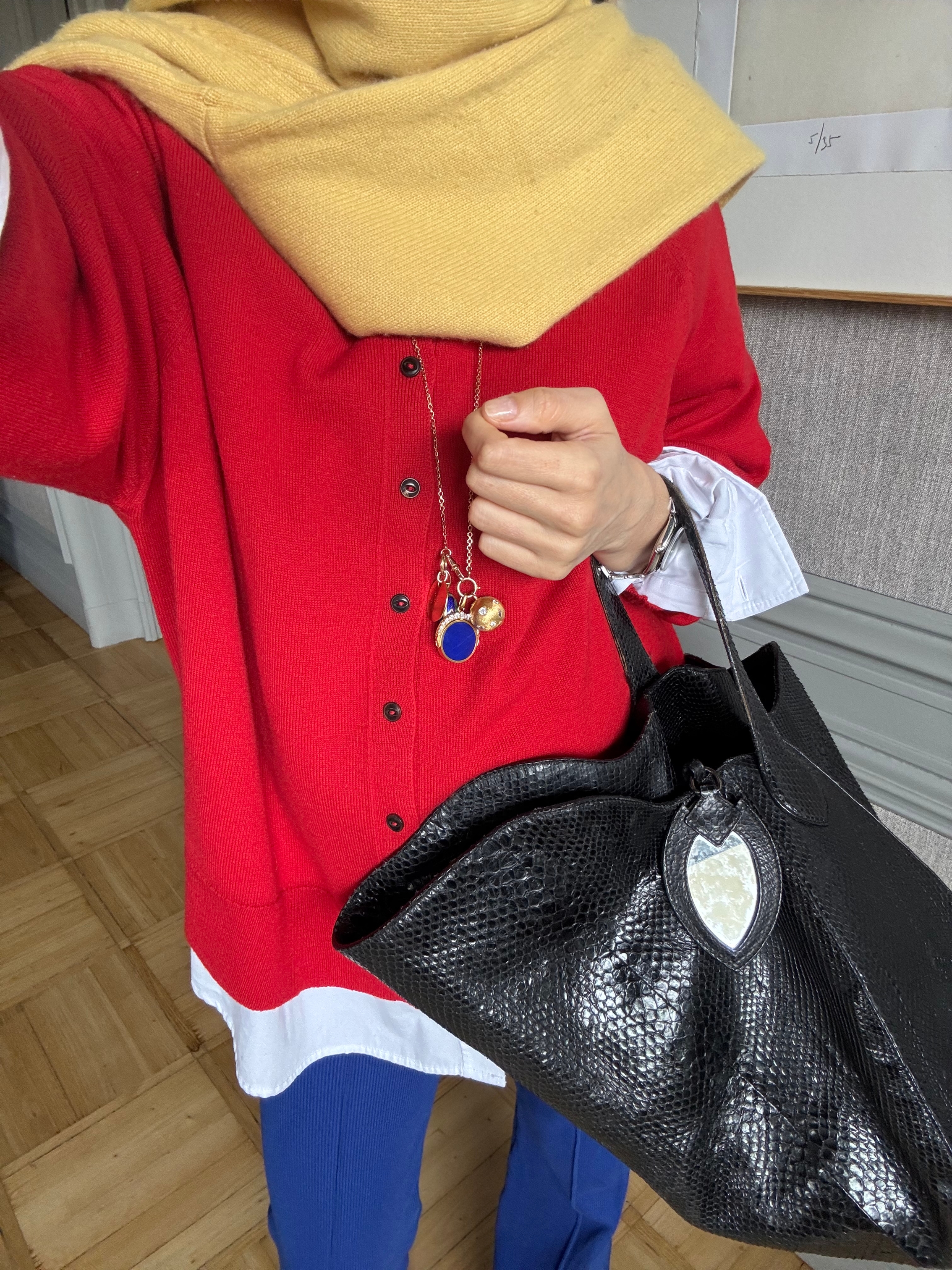 blanca miro wears a red jumper, yellow scarf and blue trousers.