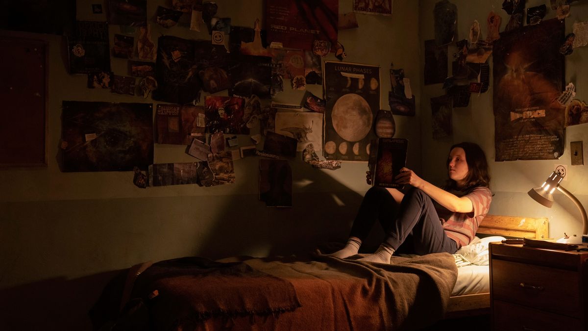 Ellie (Bella Ramsey) reading comics on her bed in The Last Of Us episode 7