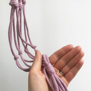 hand holding purple colour cord with wrapped knots