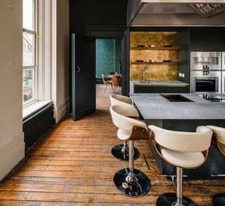Kitchen in Mimo with grey island surrounded by cream stools on a wooden floor