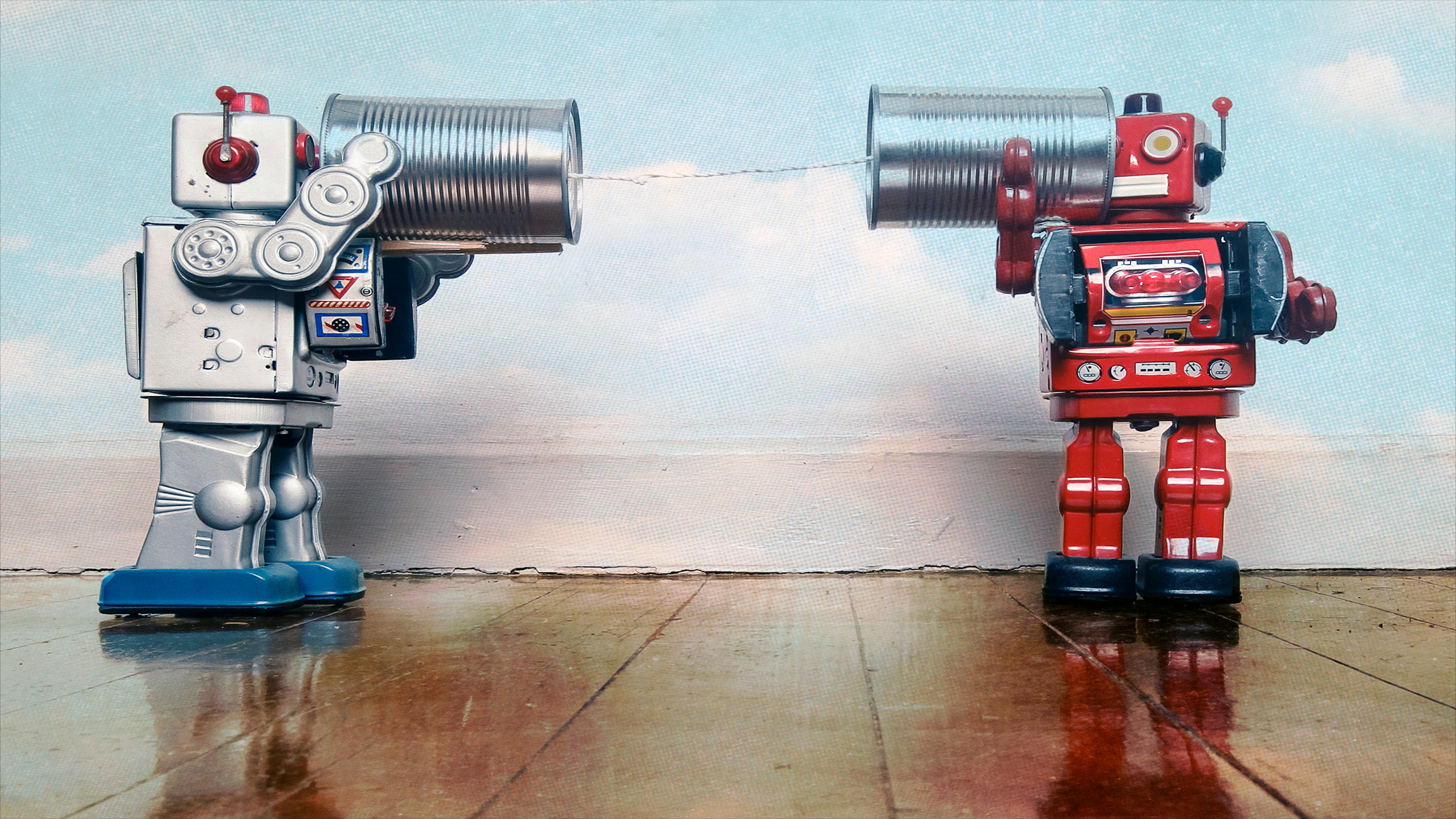 Two retro robots talk on tin can phones on an old wooden floor