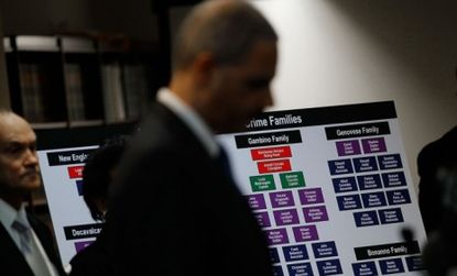 U.S. Attorney General Eric Holder stands in front of a chart outlining the hierarchy of the alleged mob families. 