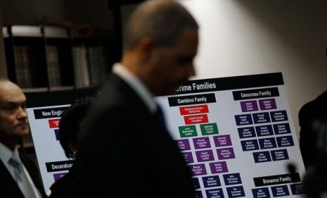 U.S. Attorney General Eric Holder stands in front of a chart outlining the hierarchy of the alleged mob families. 