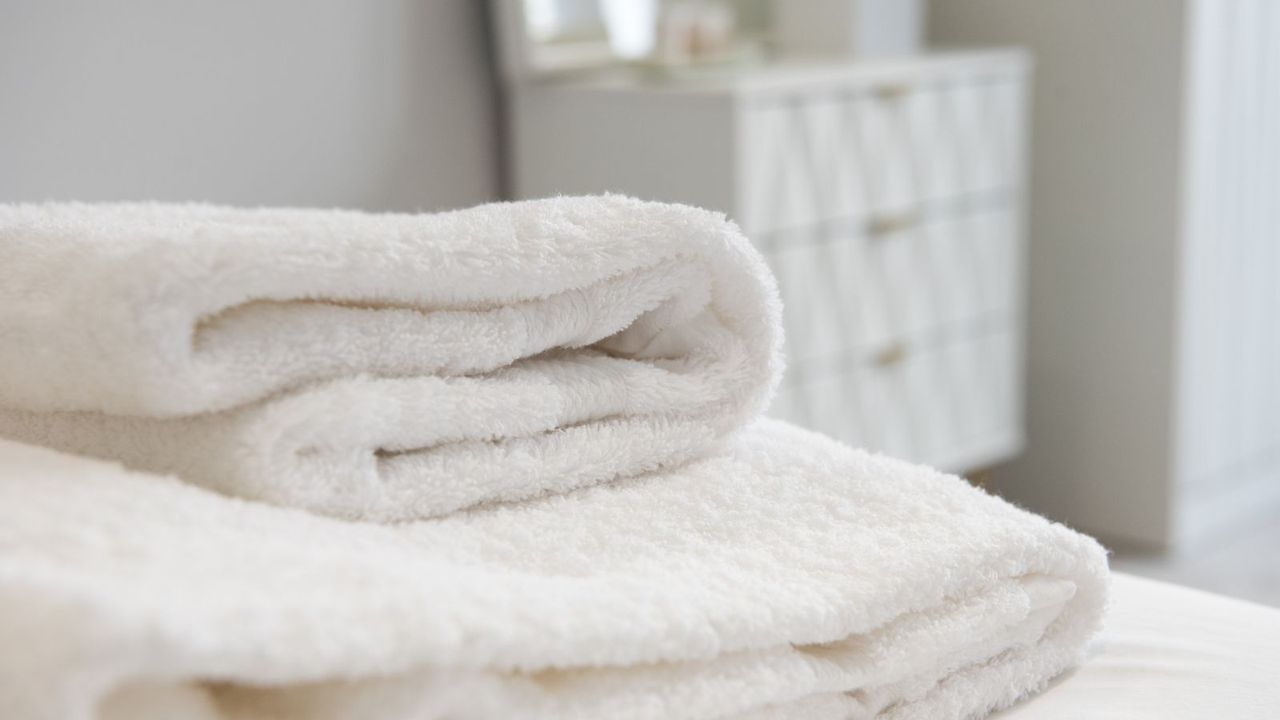 A stack of white bath towels on a bed