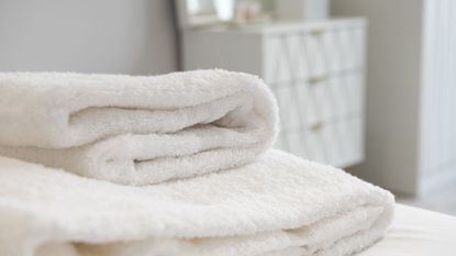 A stack of white bath towels on a bed