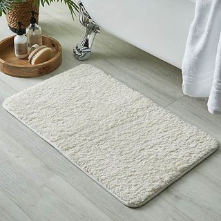 White fleece teddy bear bath mat on a bathroom floor