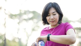 How to lose fat and gain muscle: Image shows woman looking at fitness tracker