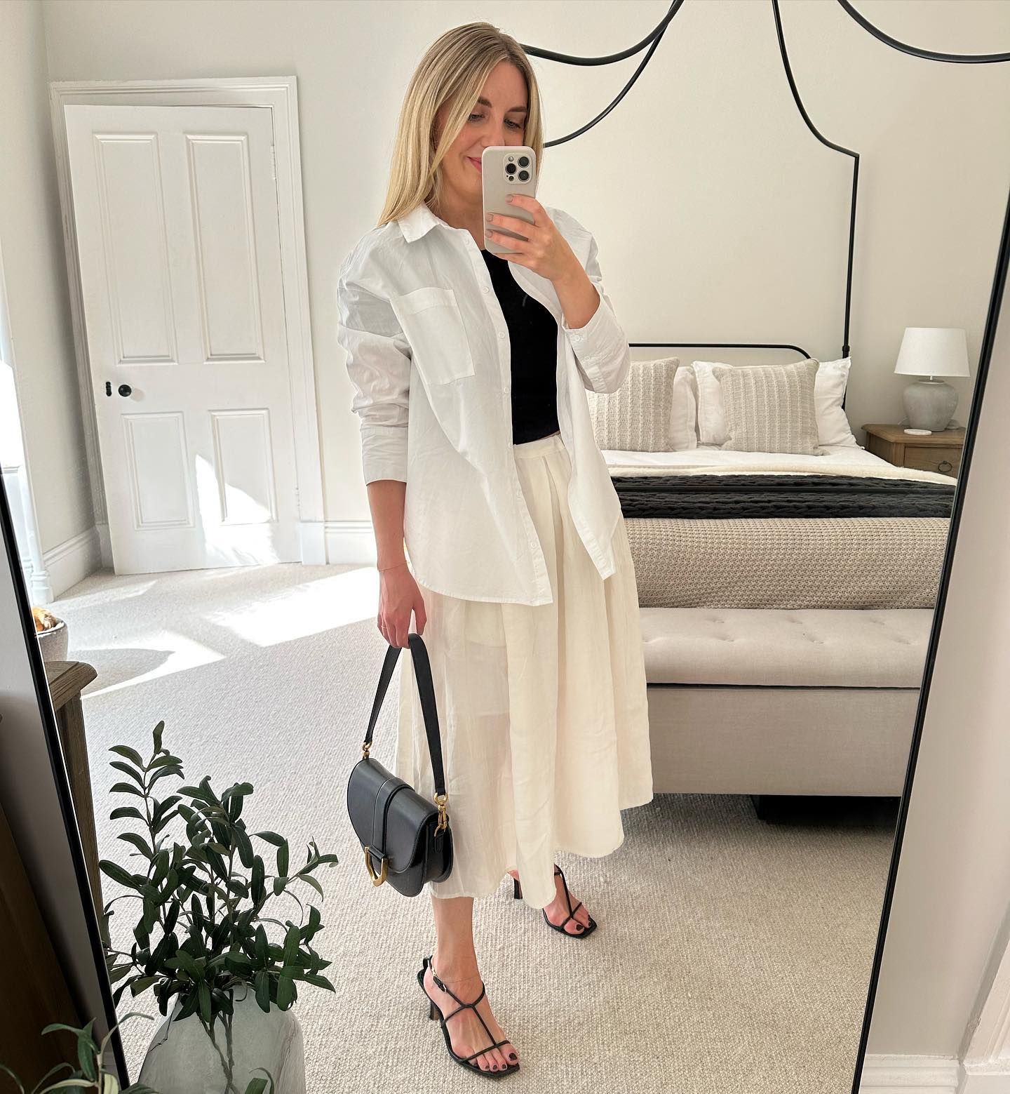 Maxine wears a white shirt, black top and cream skirt