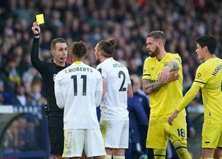 The referee shows a yellow card to Leeds' Tyler Roberts