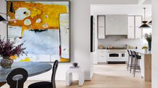 view through to kitchen from dining room with white walls and bright contemporary artwork