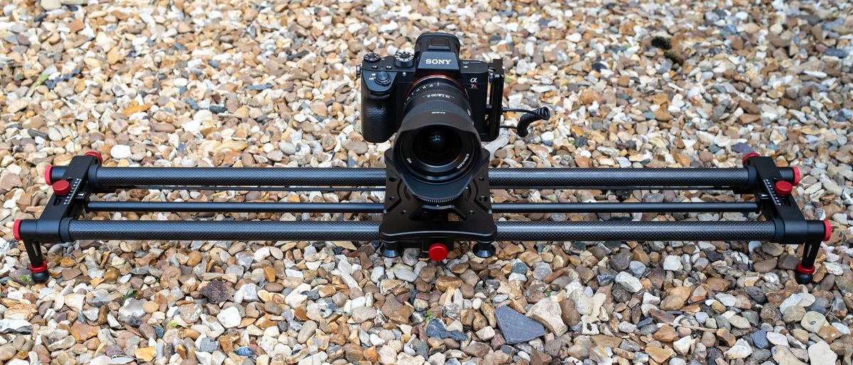 Neewer ER1 Motorized Carbon Fiber Camera Slider with a Sony camera attached outside on a stony ground