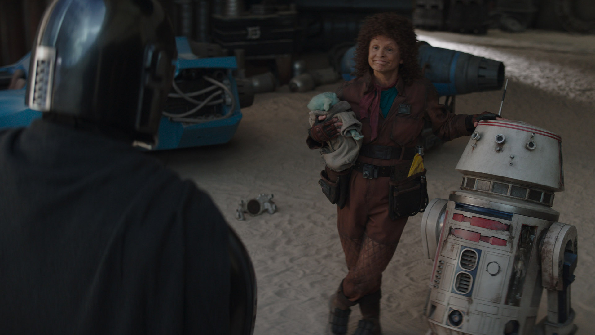 Peli Motto holds Grogu as she smiles at Din Djarin in The Mandalorian season 3