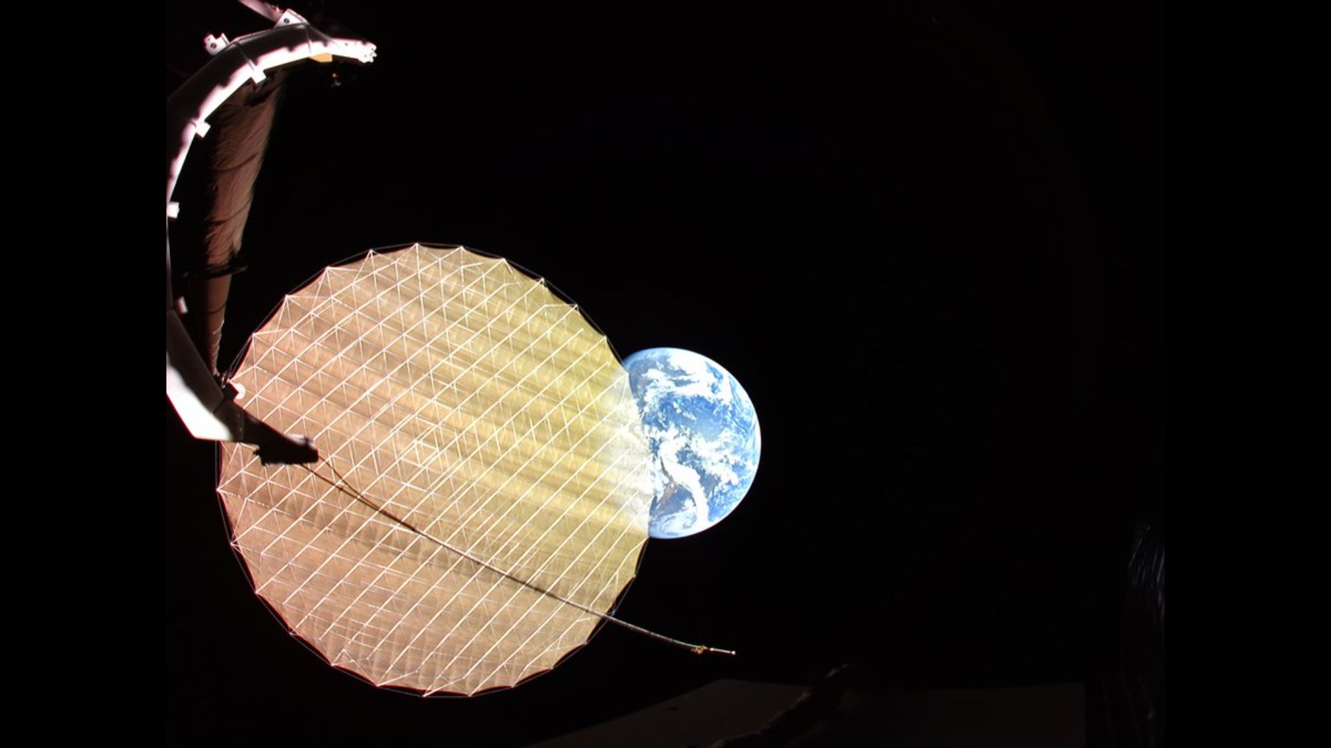 A circular, yellow honeycomb pattern reflector that is semi-transparent overlaps in front of the left third of Earth against the black of space.