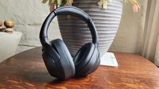 Sony ULT Wear over-ear headphones leaning up against plant pot on wooden table