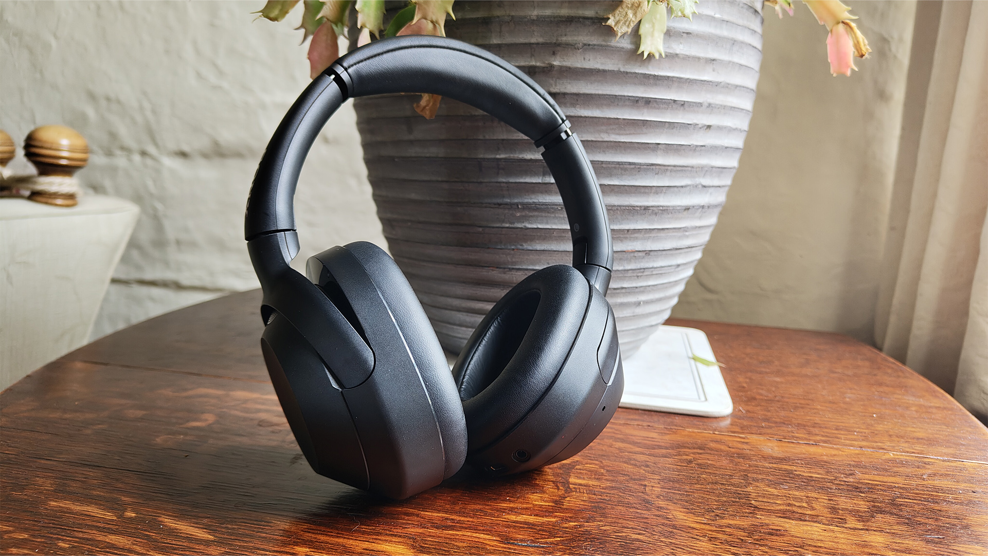 Sony ULT Wear over-ear headphones leaning up against plant pot on wooden table