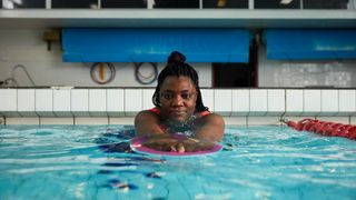 Woman swimming holding float in front of her in indoor swimming pool