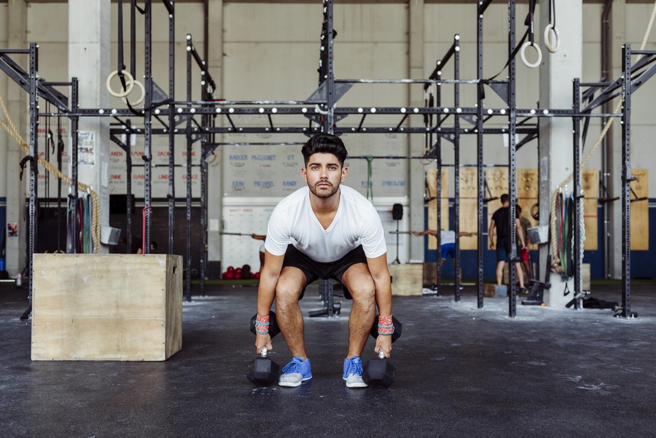 A man performing a squat with two dumbbells 