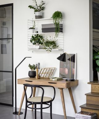 wooden desk with chair, table and floor lamps and wall mounted shelving