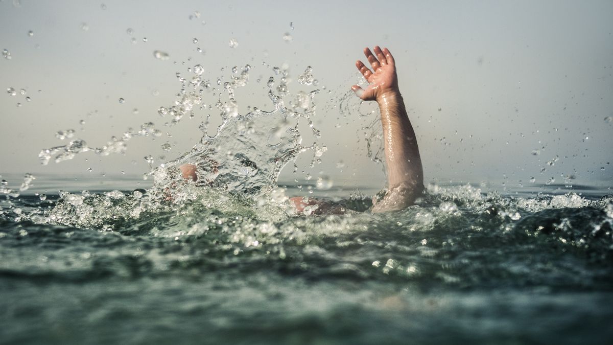 Hand reaching out of deep water, focus on water splash