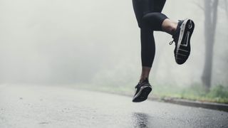 Person's feet running on road in the rain