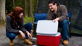 how to keep your tent clean while camping: couple with a camping cooler