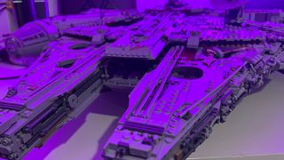 A front-on, close-up view of the Lego UCS Millennium Falcon bathed in purple light
