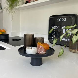 Candles arranged on a black stoneware cake stand to create a display on a kitchen breakfast bar