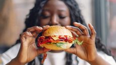 A woman holds up a hamburger
